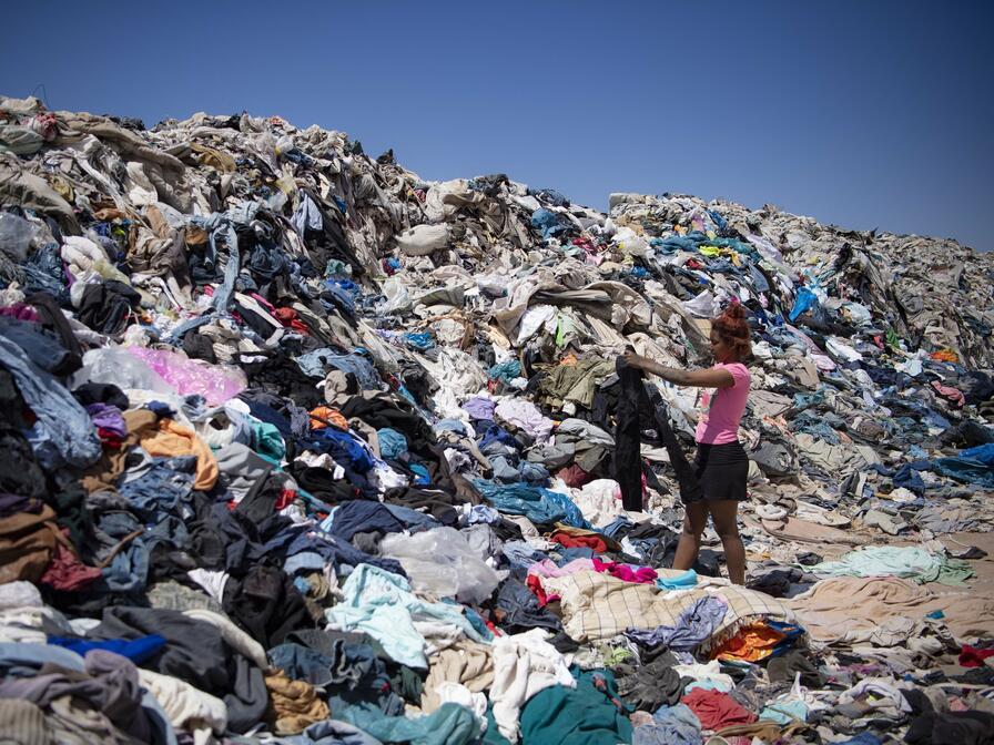 Žena prehrabujúca sa oblečením vyradenej "rýchlej módy" z Európy na skládke v púšti Atacama&nbsp;
